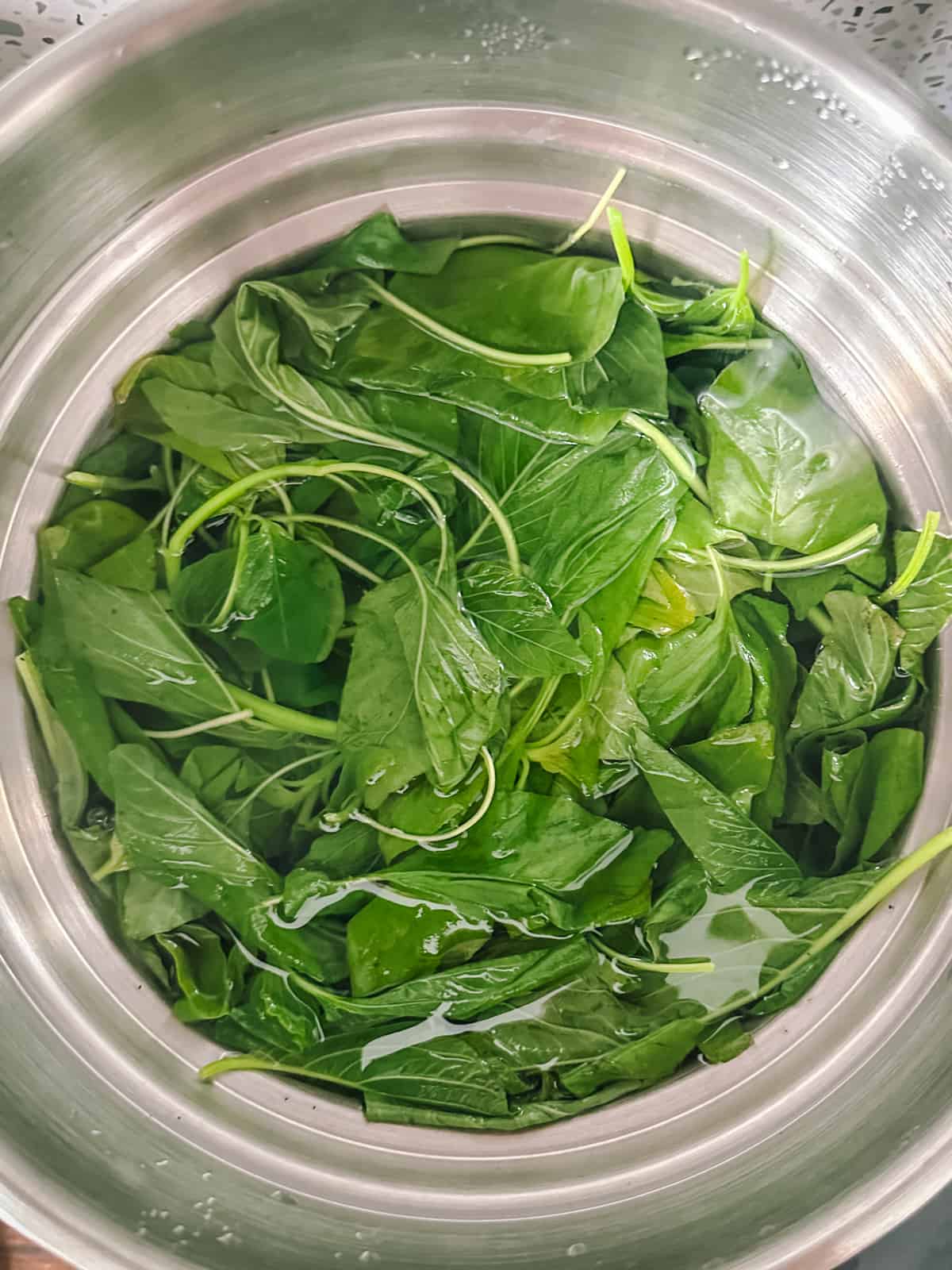 Greens cooking in a large pot filled with water.