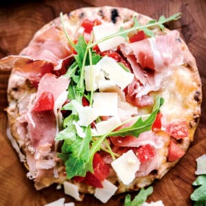 A pita pizza with arugula, prosciutto and parmesan.