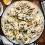 A plate with roasted cauliflower steaks with dill, capers and parmesan cheese.