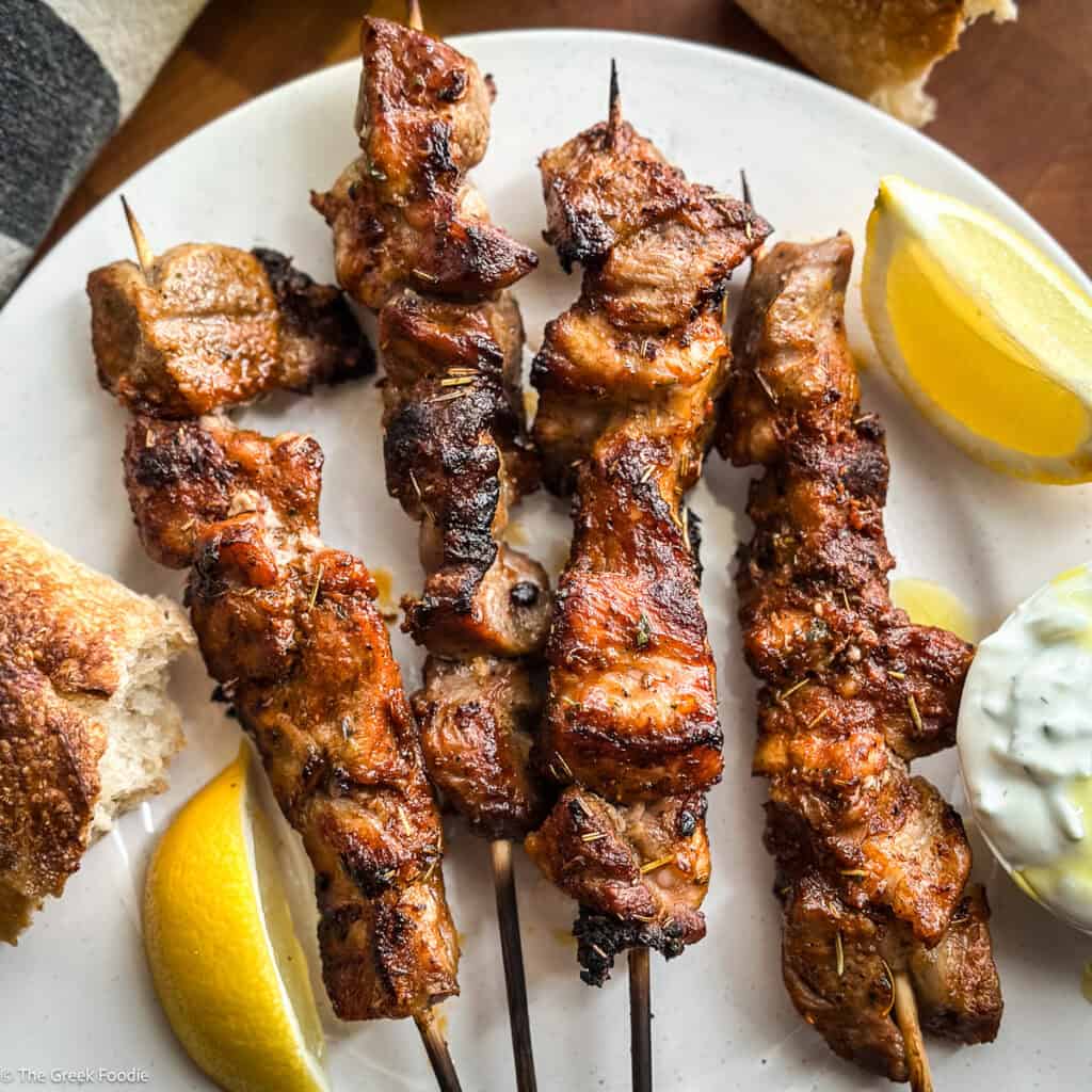 Greek pork souvlaki Kalamaki skewers with bread and lemon wedges