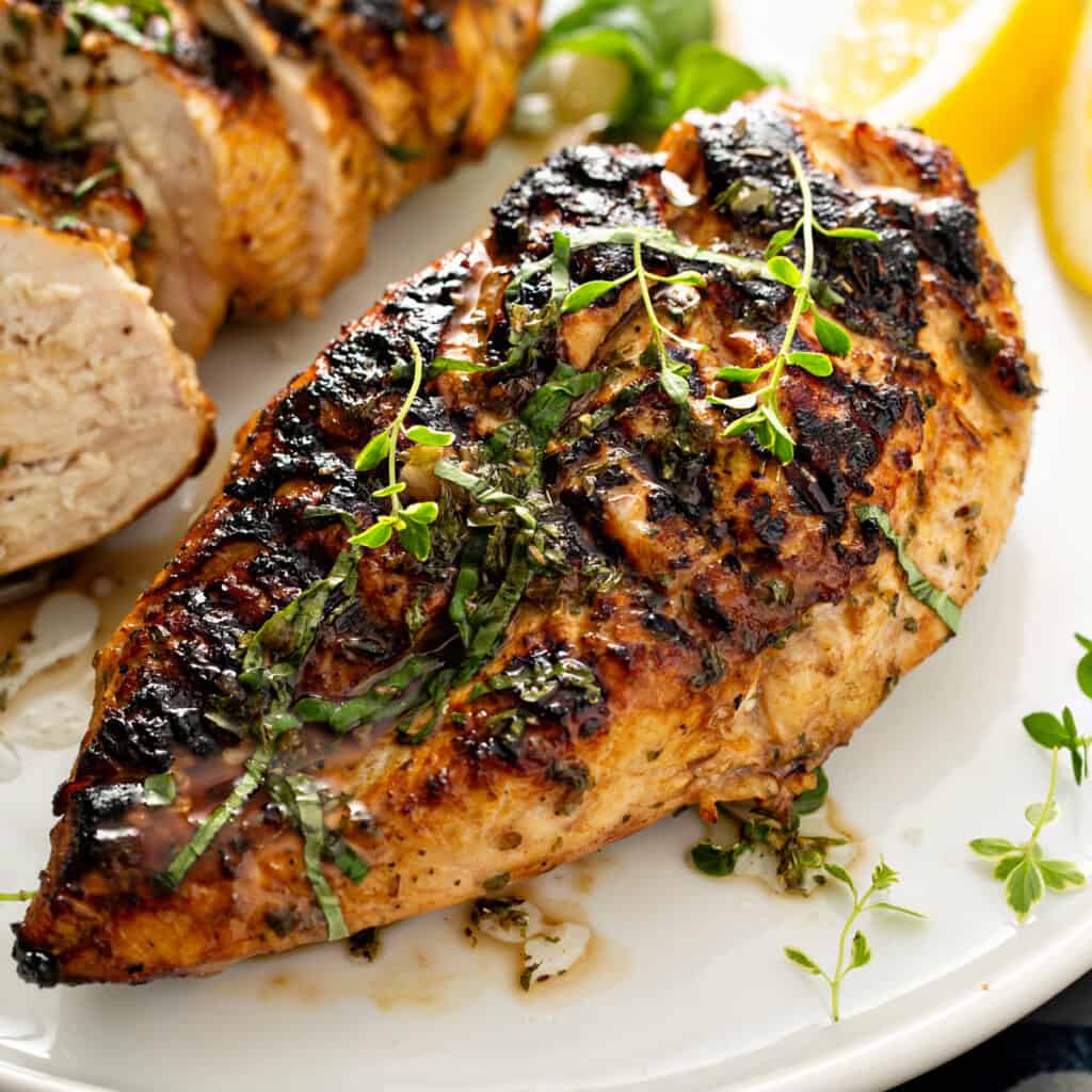 Close up of a grilled chicken breast with herbs.