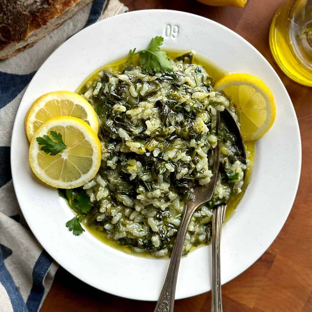Spinach and rice on a plate with lemon slices and a spoon.