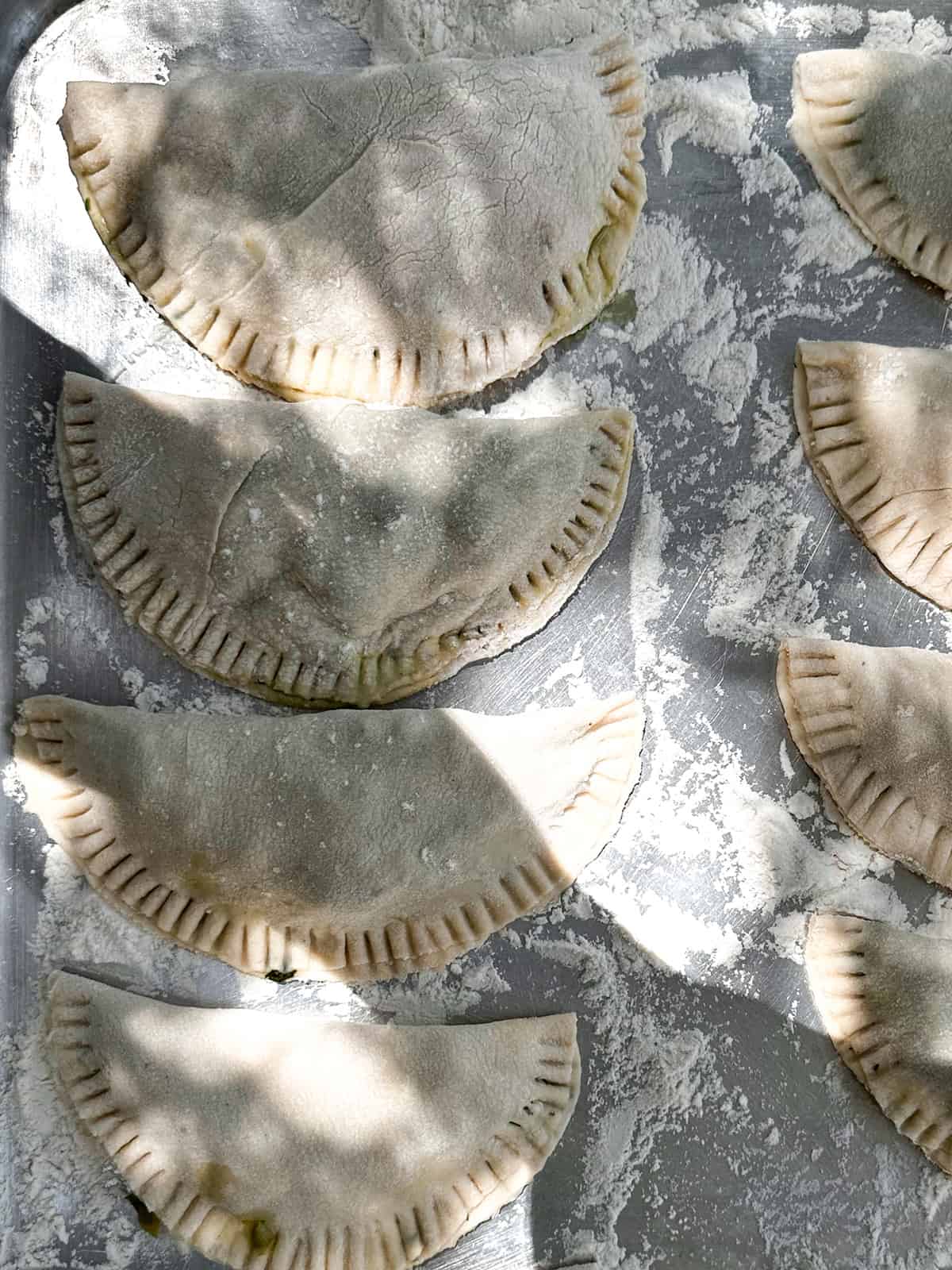 Close up of hand pies on a floured baking sheet.