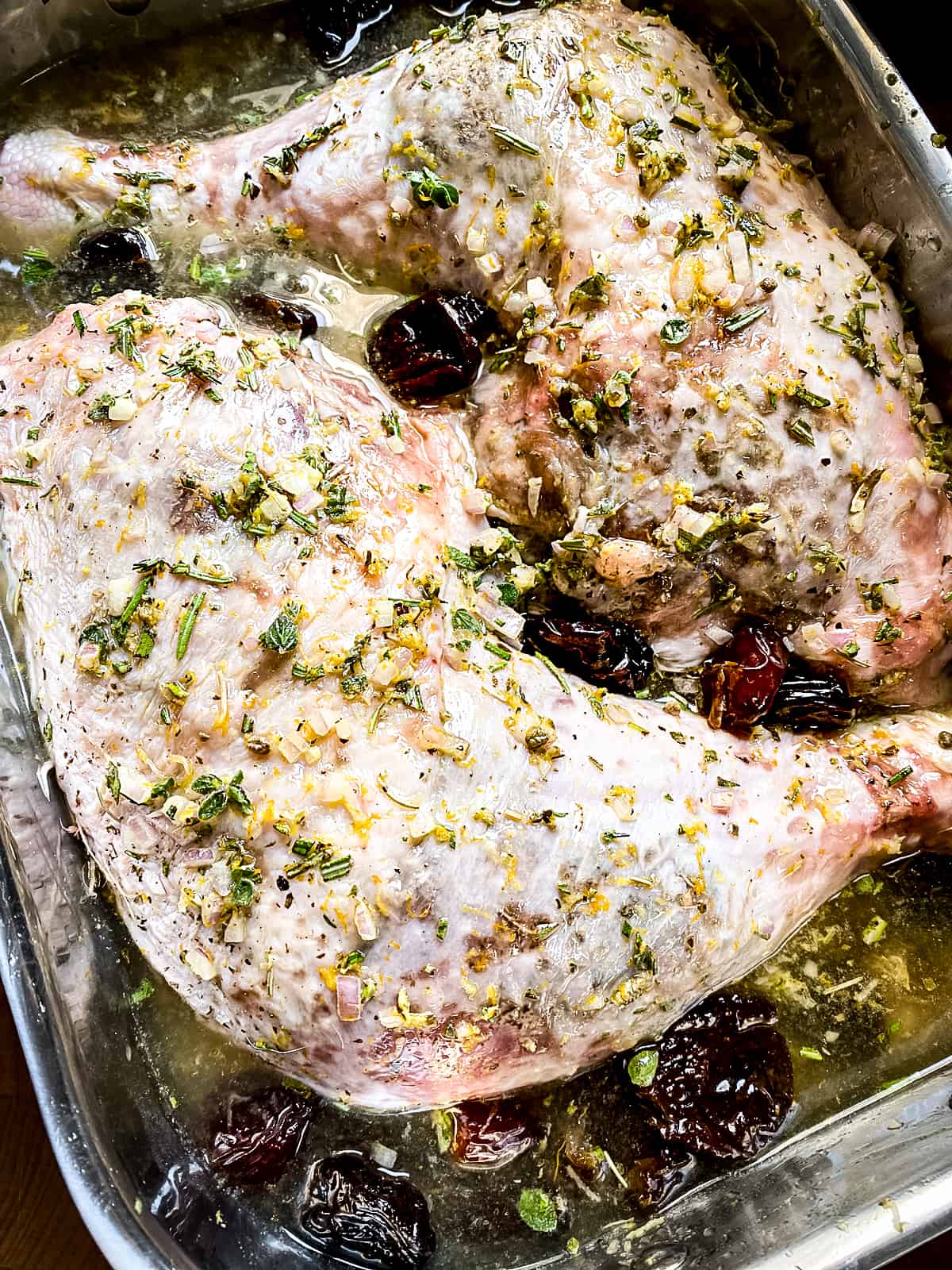 Turkey thighs with marinate all over them in a baking pan.