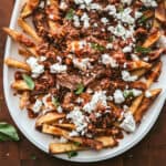 A platter with Greek loaded fries with feta and herbs.