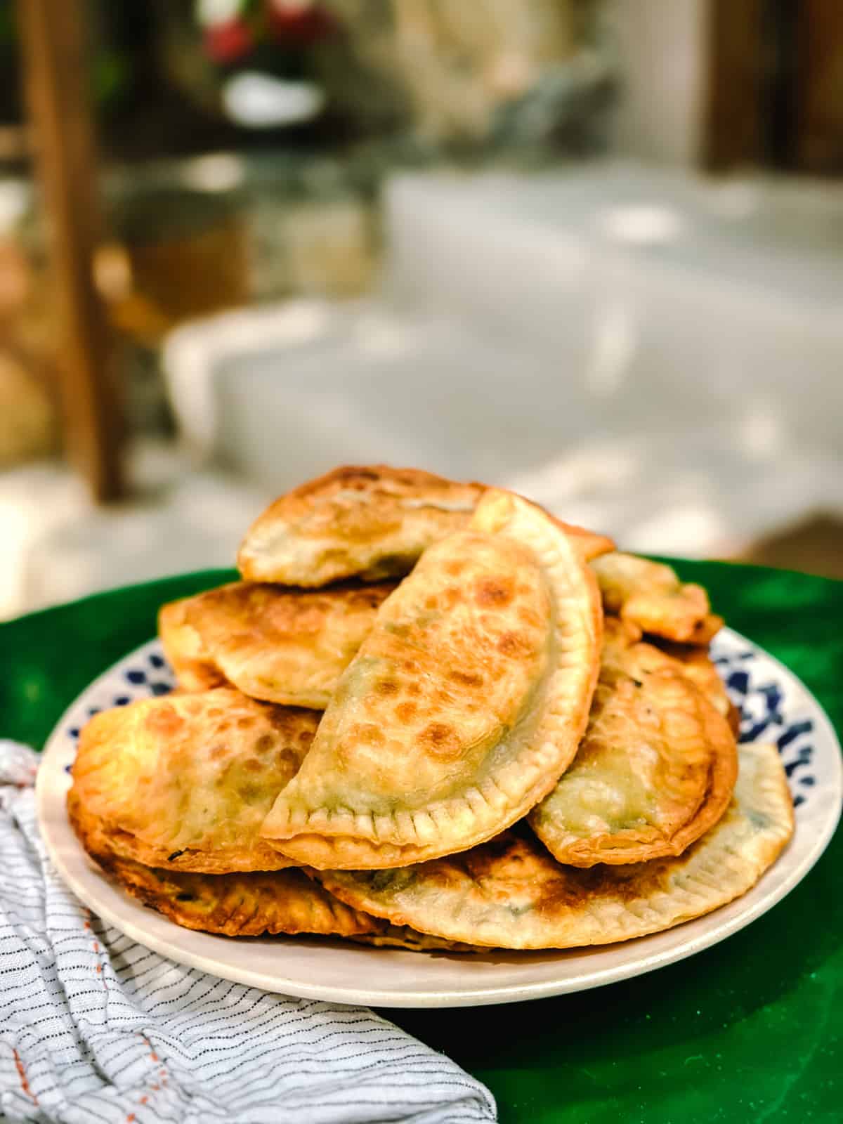 Kalitsounia, Cretan hand pies from Chania in a plate with a cloth napkin on a dark green table.