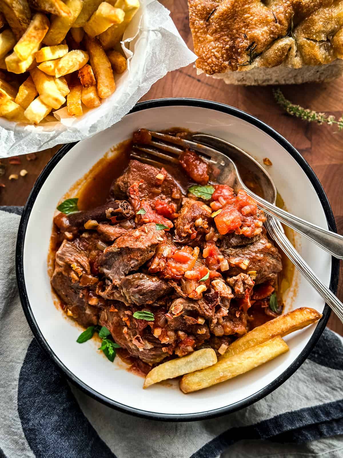 Kokkinisto, Greek braised beef in tomato sauce, on a plate with fries.