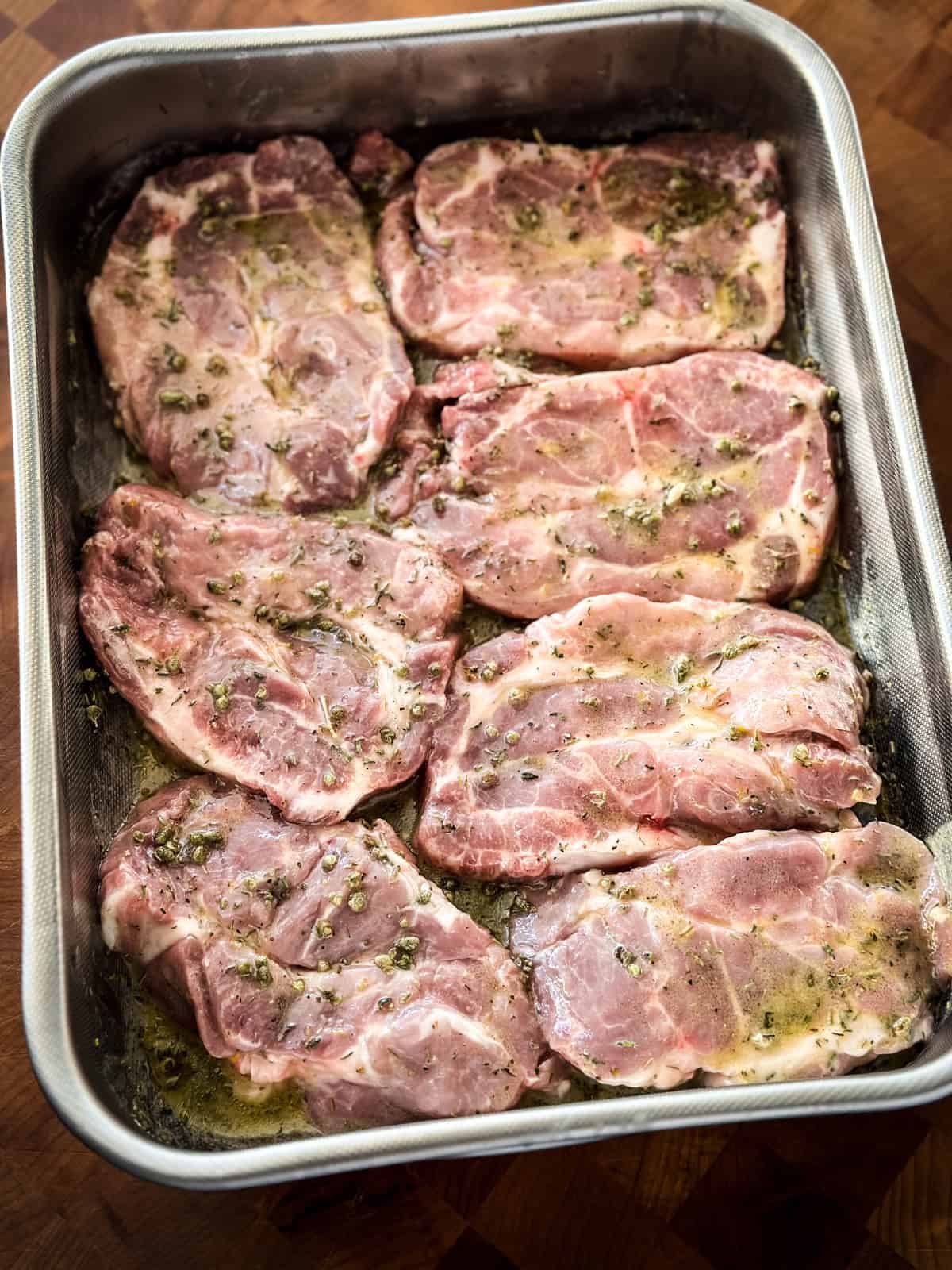 Pork steaks in a roasting pan marinating.