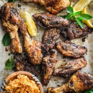 Platter of Greek chicken chops with basil, lemon, and a bowl of whipped feta dip