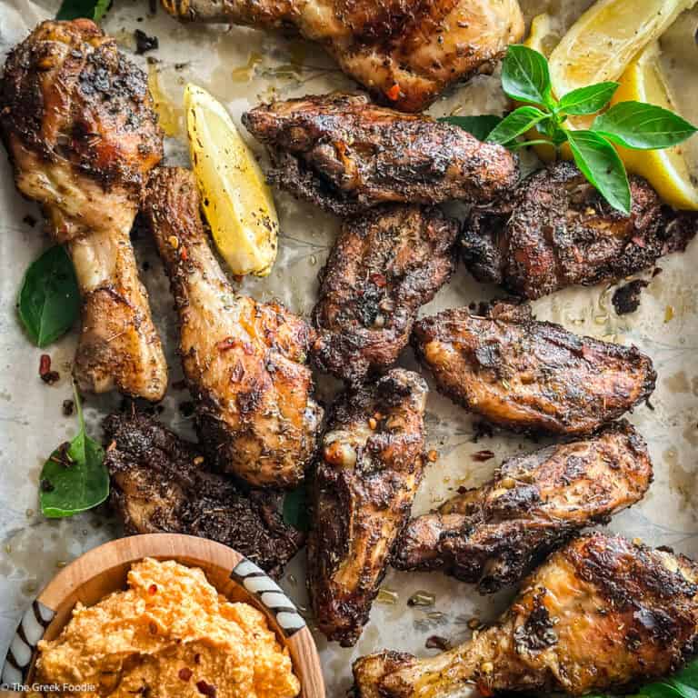 Platter of Greek chicken chops with basil, lemon, and a bowl of whipped feta dip