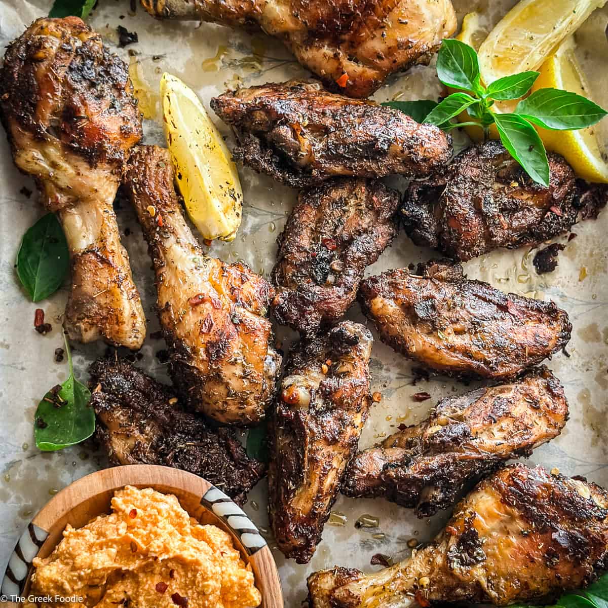 Platter of Greek chicken chops with basil, lemon, and a bowl of whipped feta dip
