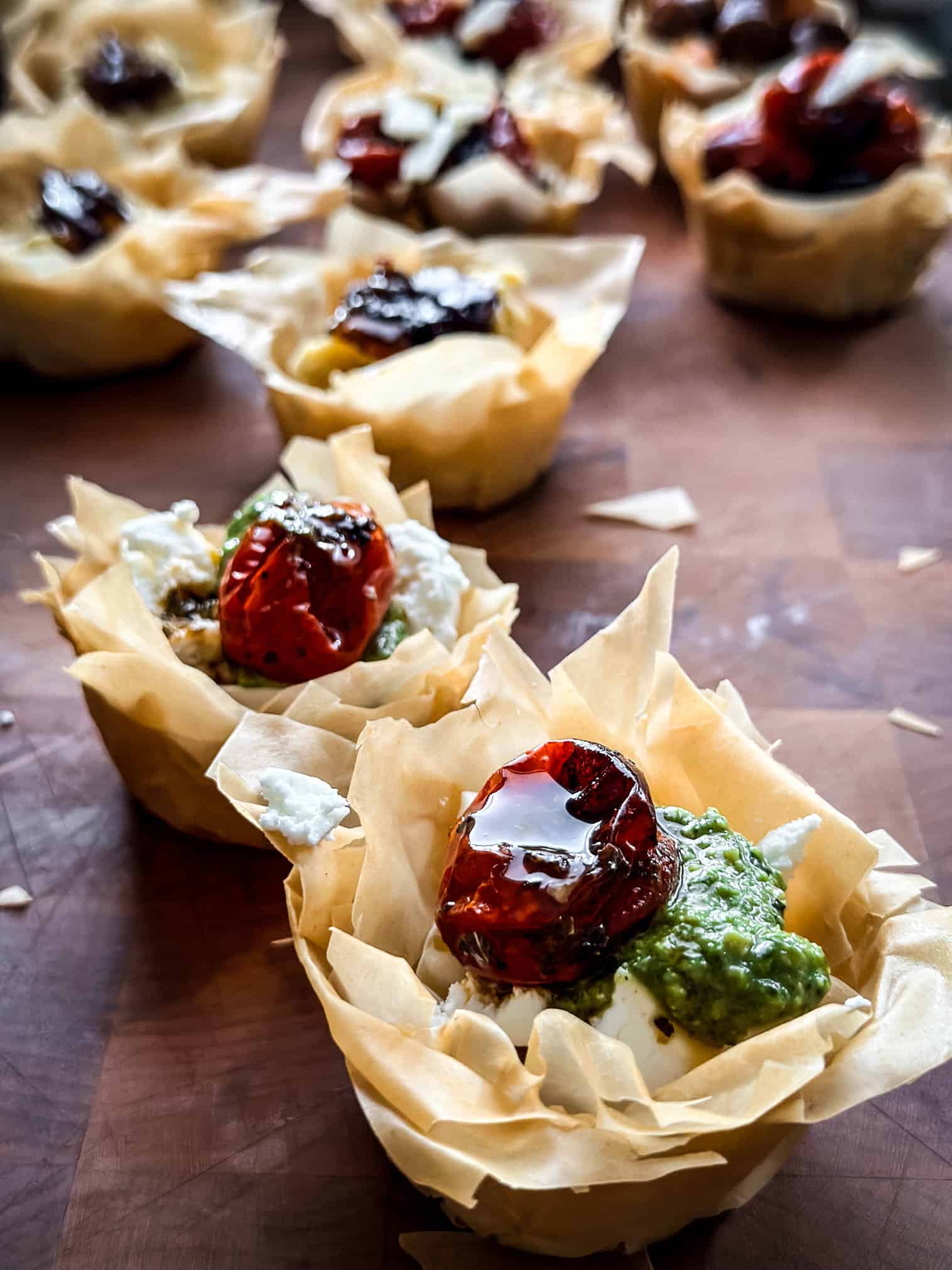 A phyllo cup appetizer with tomato and pesto.