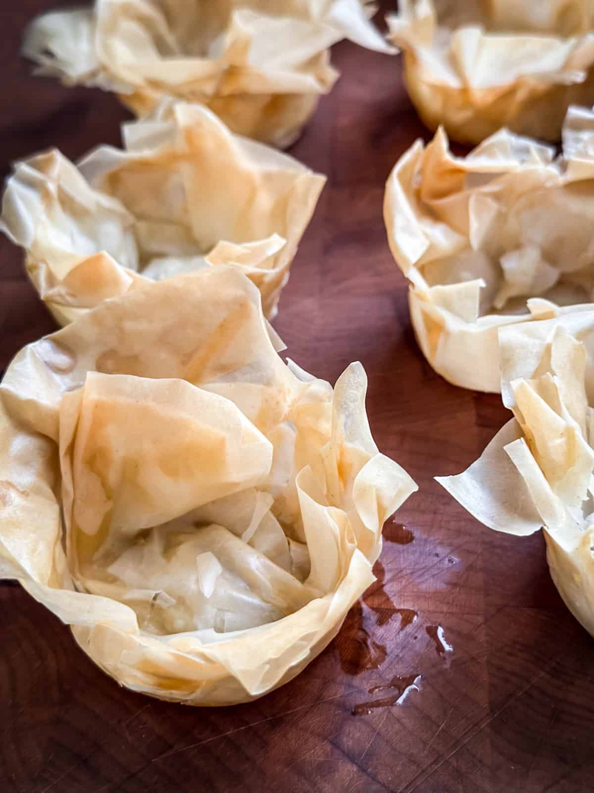 Just baked phyllo cups lined up on wood.