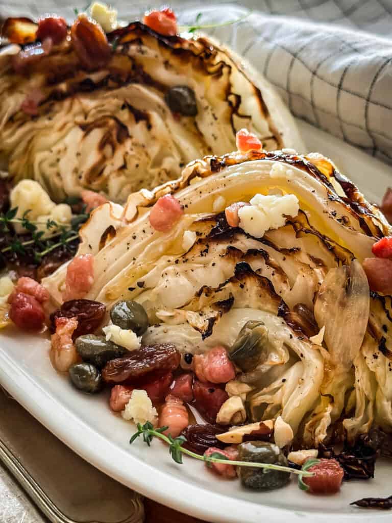 Two roasted cabbage wedges with raisin caper and bacon sauce.