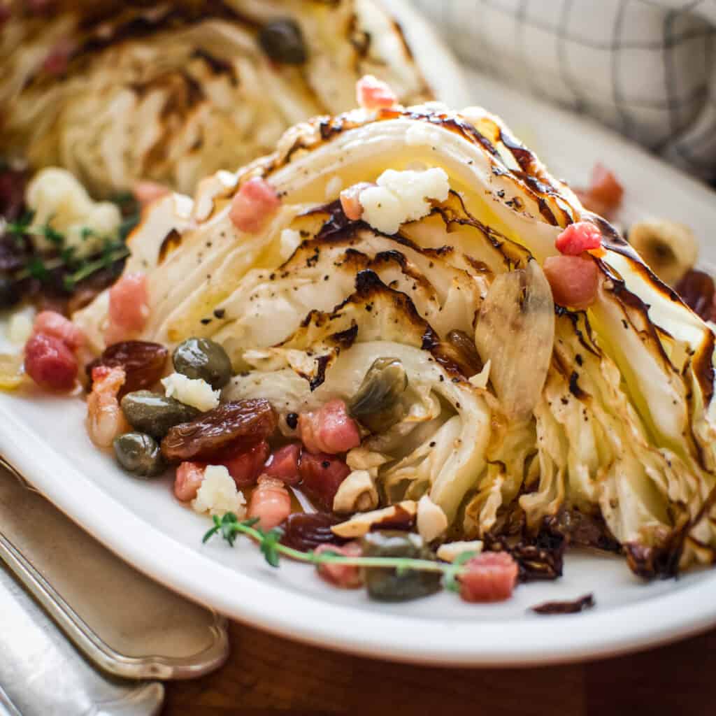 A roasted cabbage wedge with raisin caper and bacon sauce.