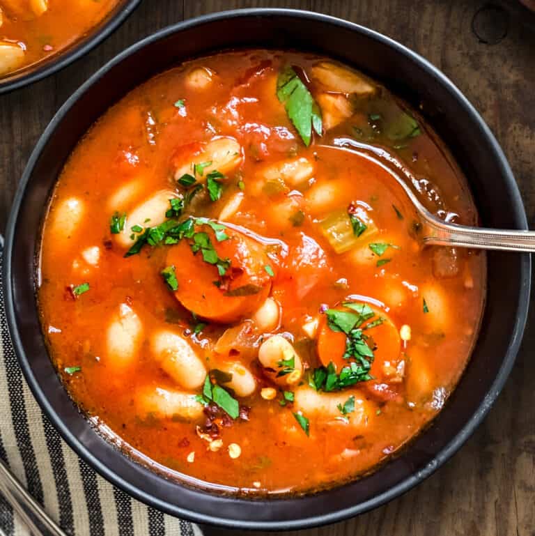 Fasolada-Greek white bean soup, in bowl with a spoon.