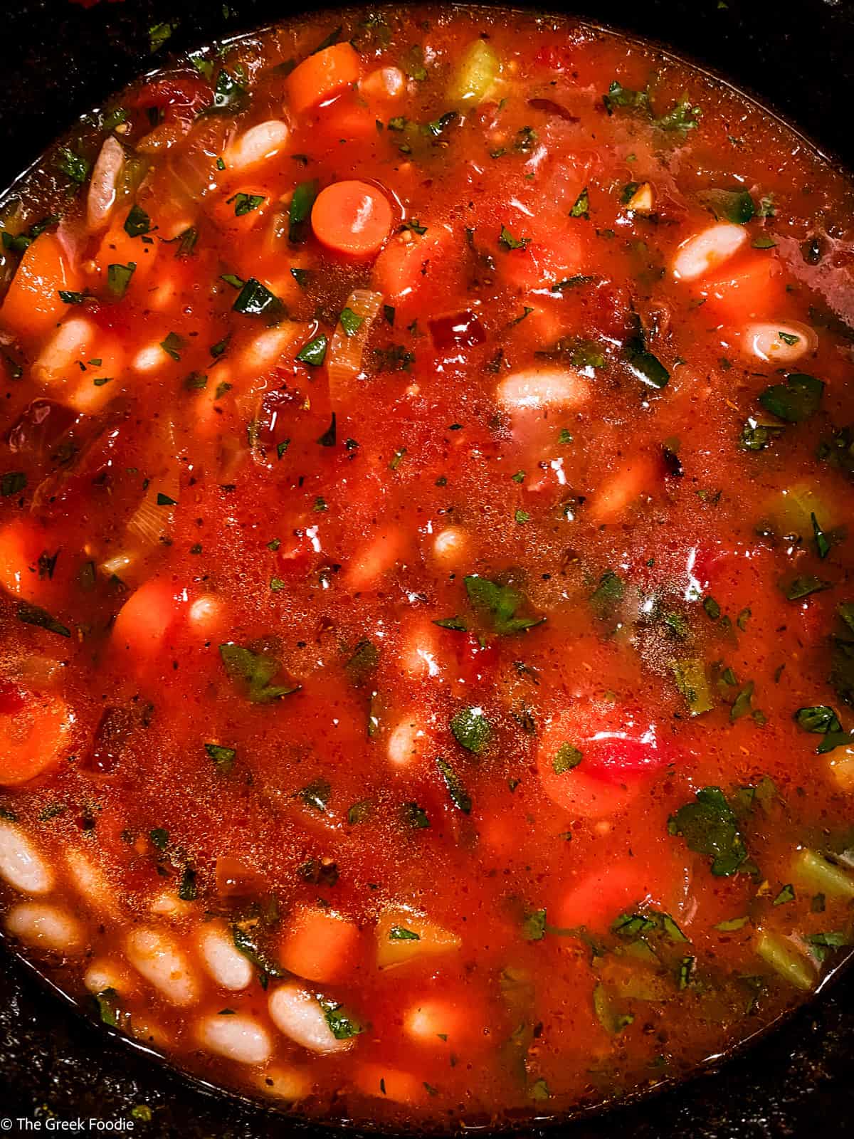 Beans, 
carrots, celery and parsley in a pot cooking.