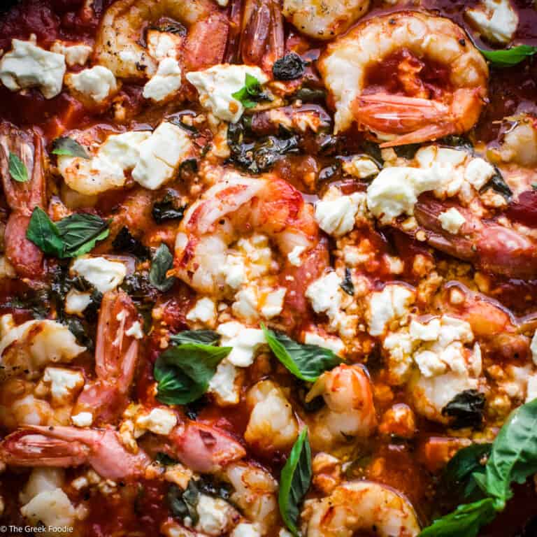 A yellow cast iron with shrimp saganaki in tomato sauce.