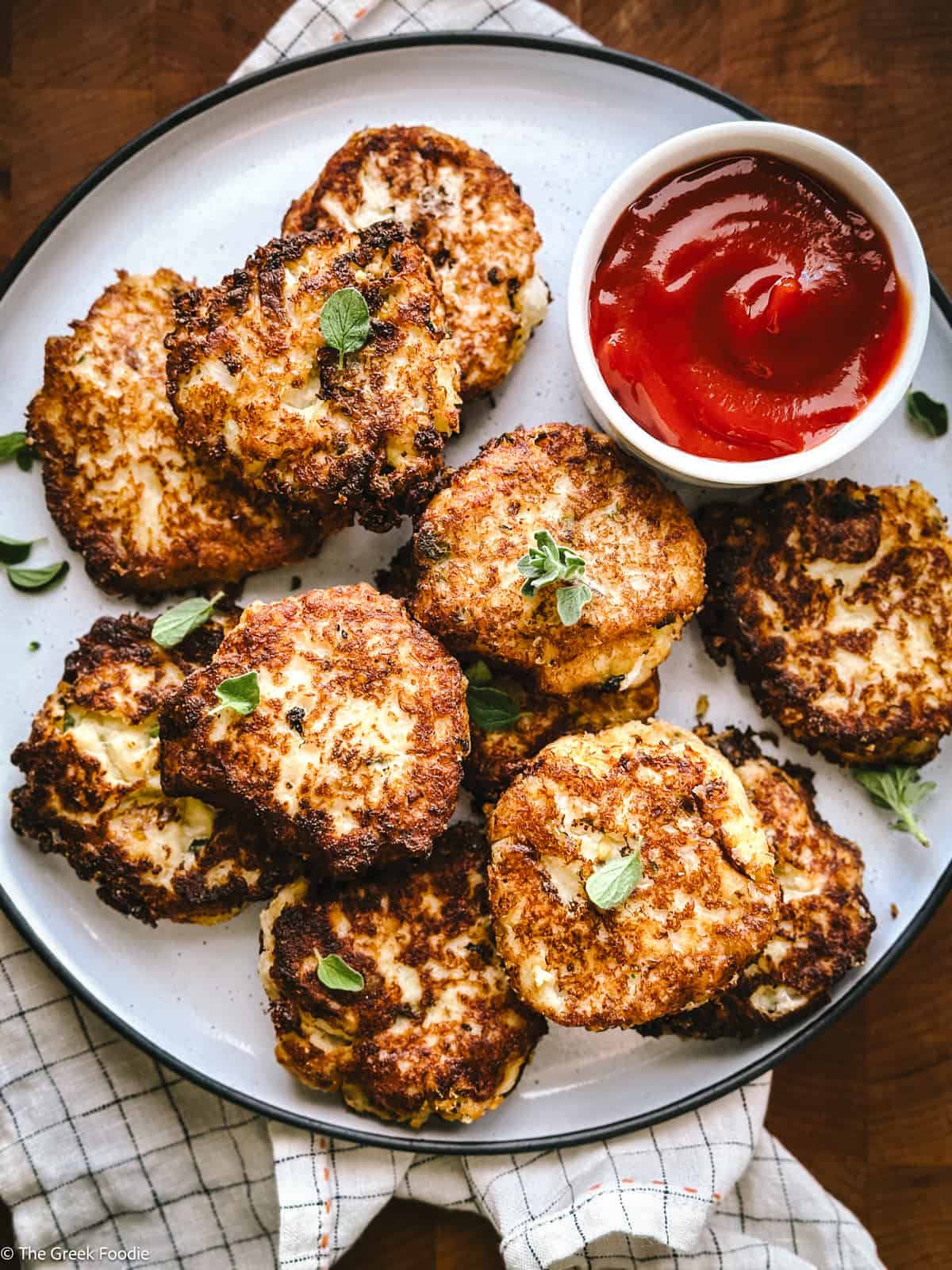 Cauliflower fritters on a plate with a cup with ketchup.