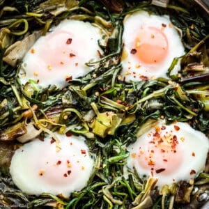 Four cooked eggs and greens.