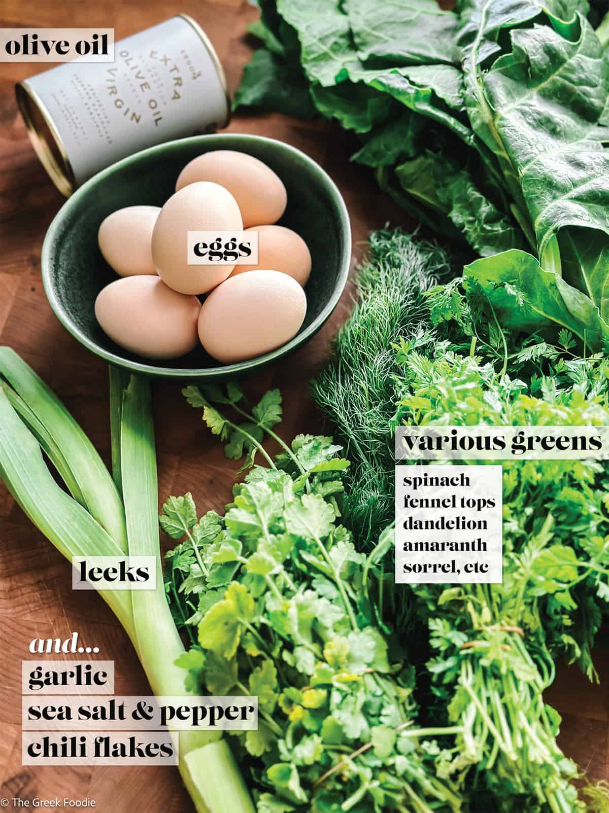 Eggs in a bowl, a can with olive oil, leeks and lots of greens on a table.