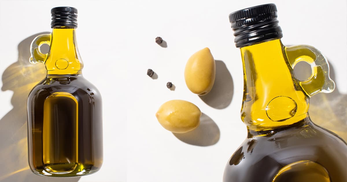 A bowl with olives, a saucier with olive oil and a glass bottle with olive oil in a bright, white environment.