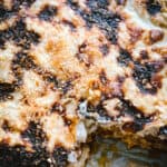 Pastitsio in a baking pan with a peice cut out.