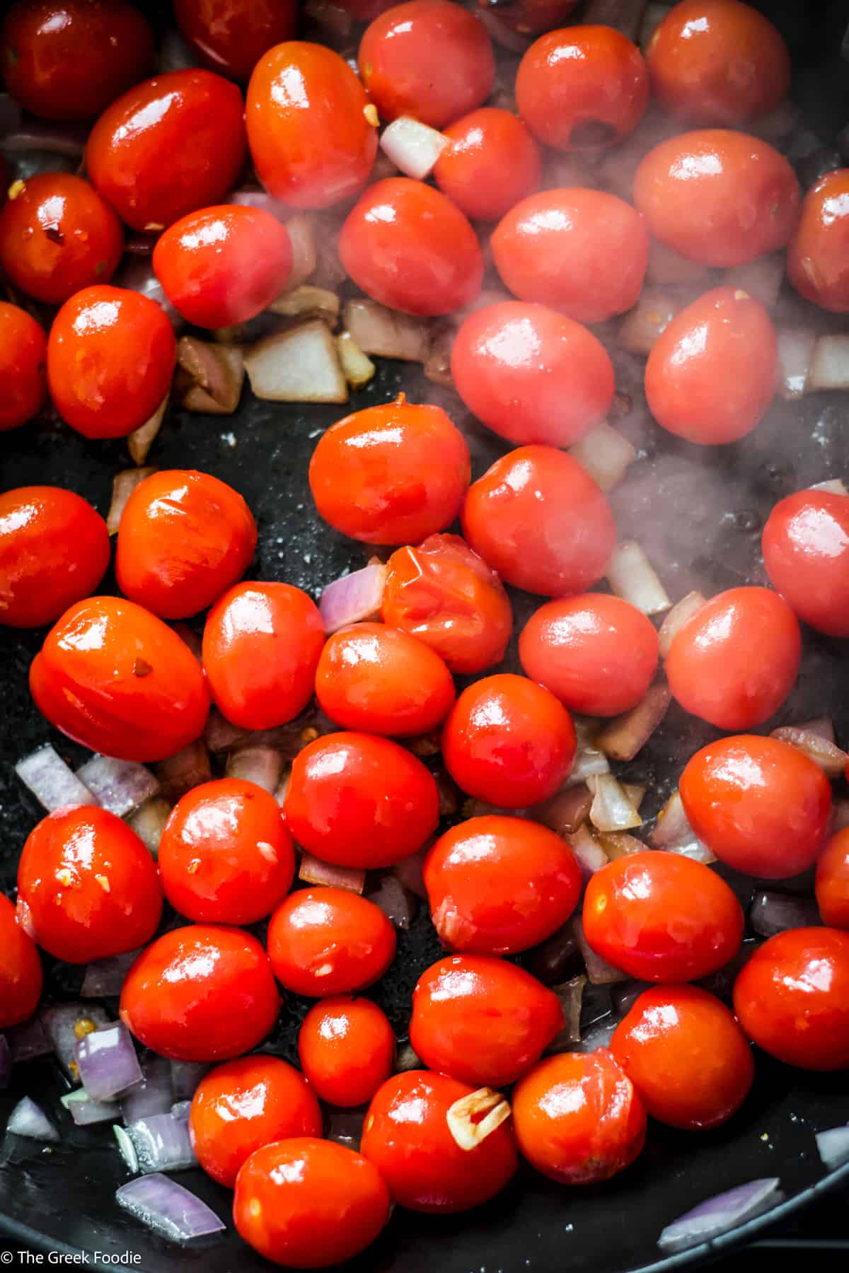 Cherry tomatoes, diced onion and garlic in a deep skillet.