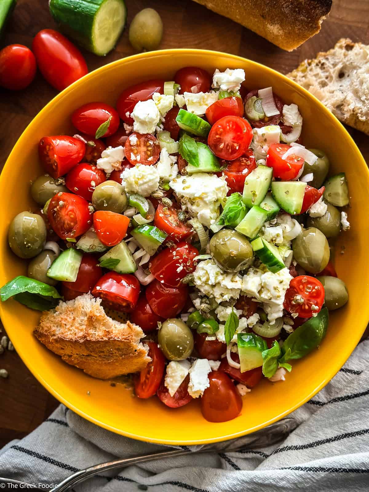 A cherry tomato salad with a piece of bread on a yellow plate.