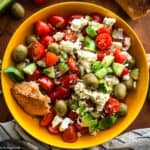 A cherry tomato salad with a piece of bread on a yellow plate.