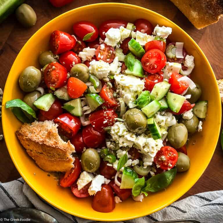 A cherry tomato salad with a piece of bread on a yellow plate.