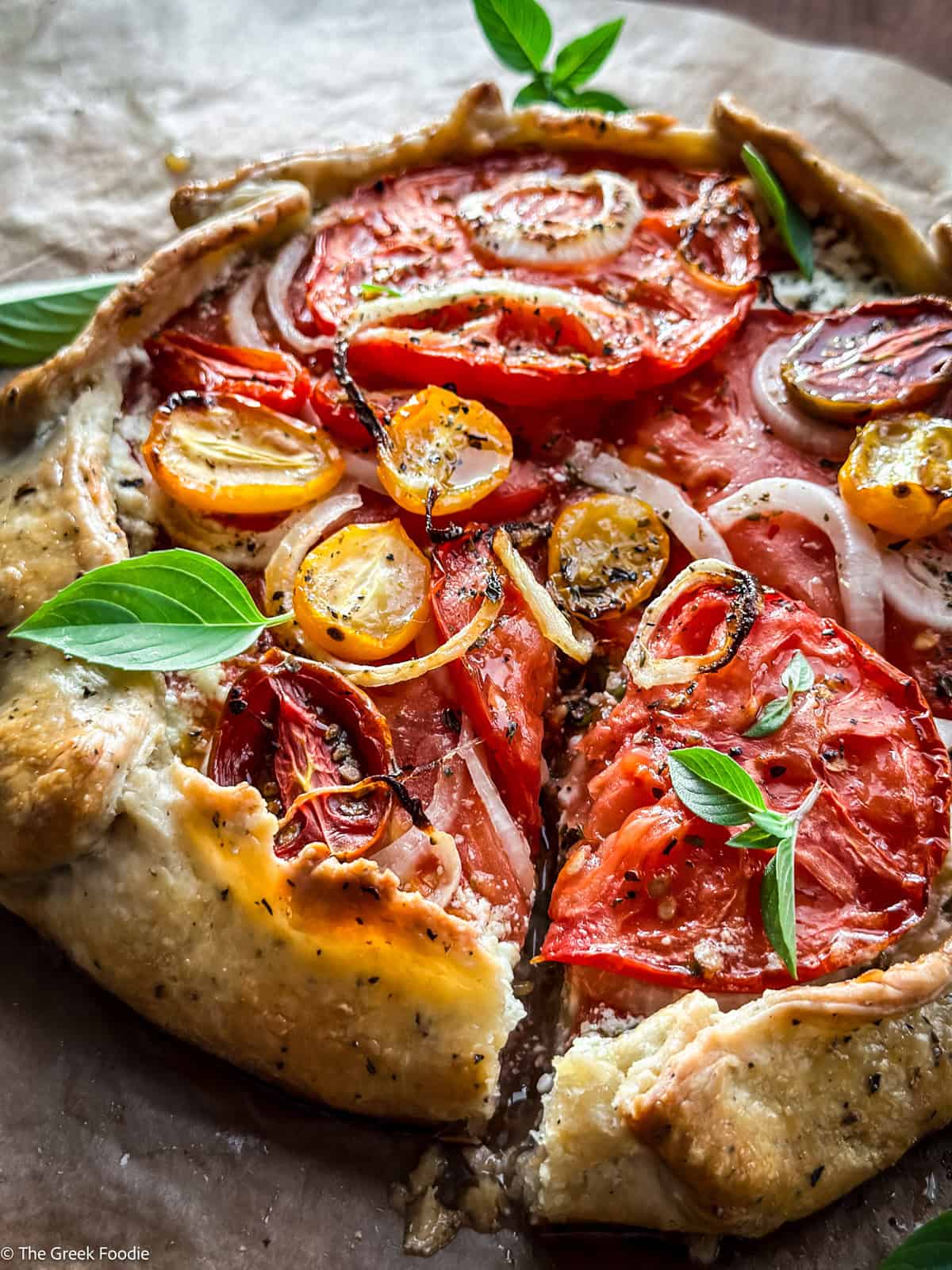A tomato galette with feta cheese, onions and tomatoes on a cutting board.