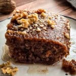 A piece of Karidopita-Greek Walnut Cake on a plate on a wooden table.