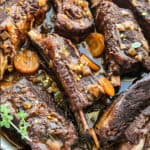Braised shorts ribs with carrots and herbs in a white plale.