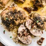 Feta stuffed chicken thighs, whole and sliced on a plate.