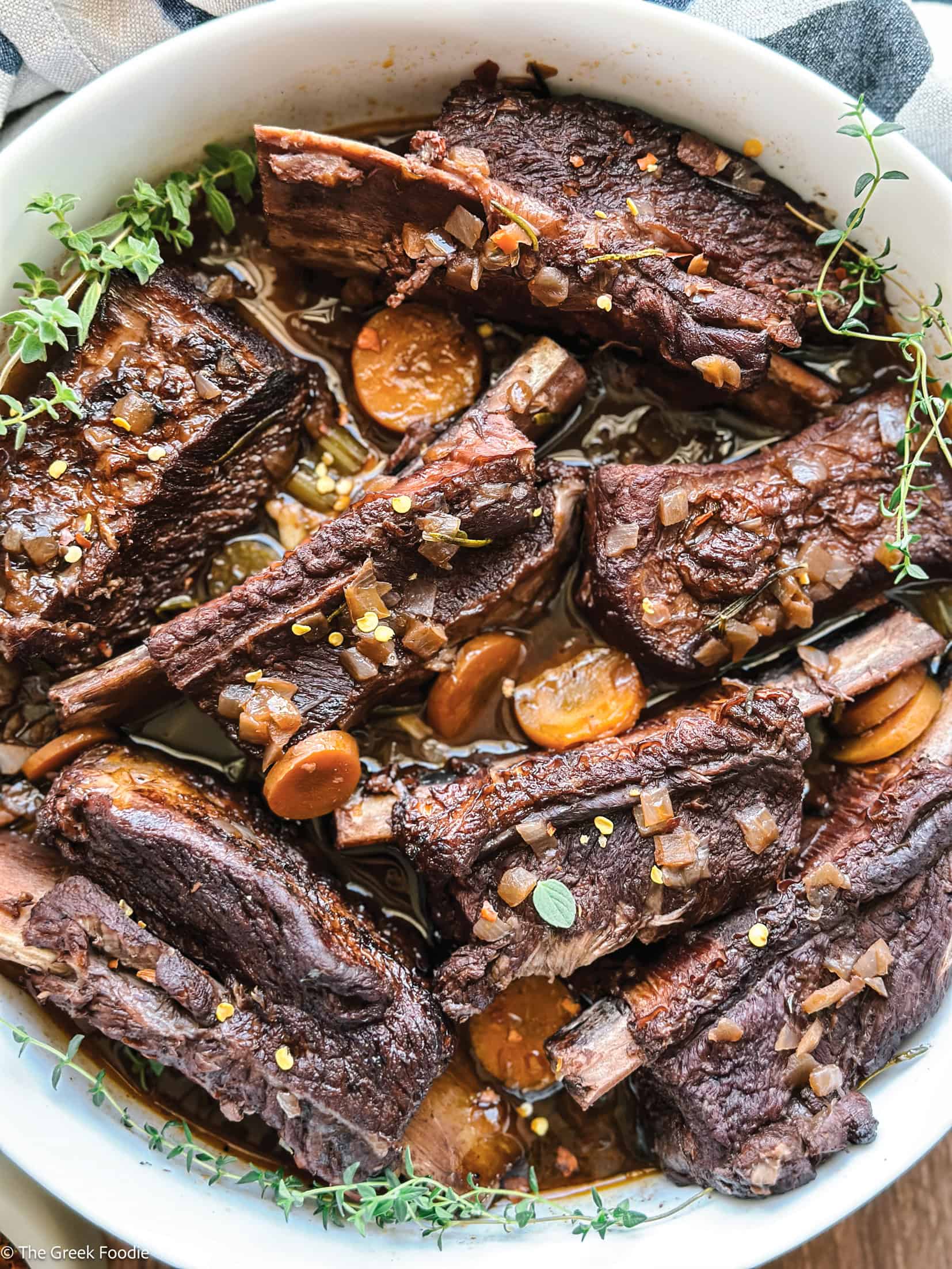 Braised beef short ribs in red wine sauce with carrots and herbs served with olive oil mashed potatoes