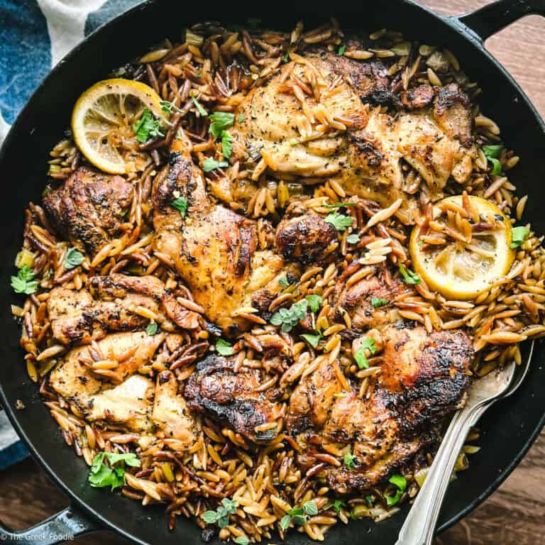 Greek lemon chicken orzo in a skillet with lemon slices