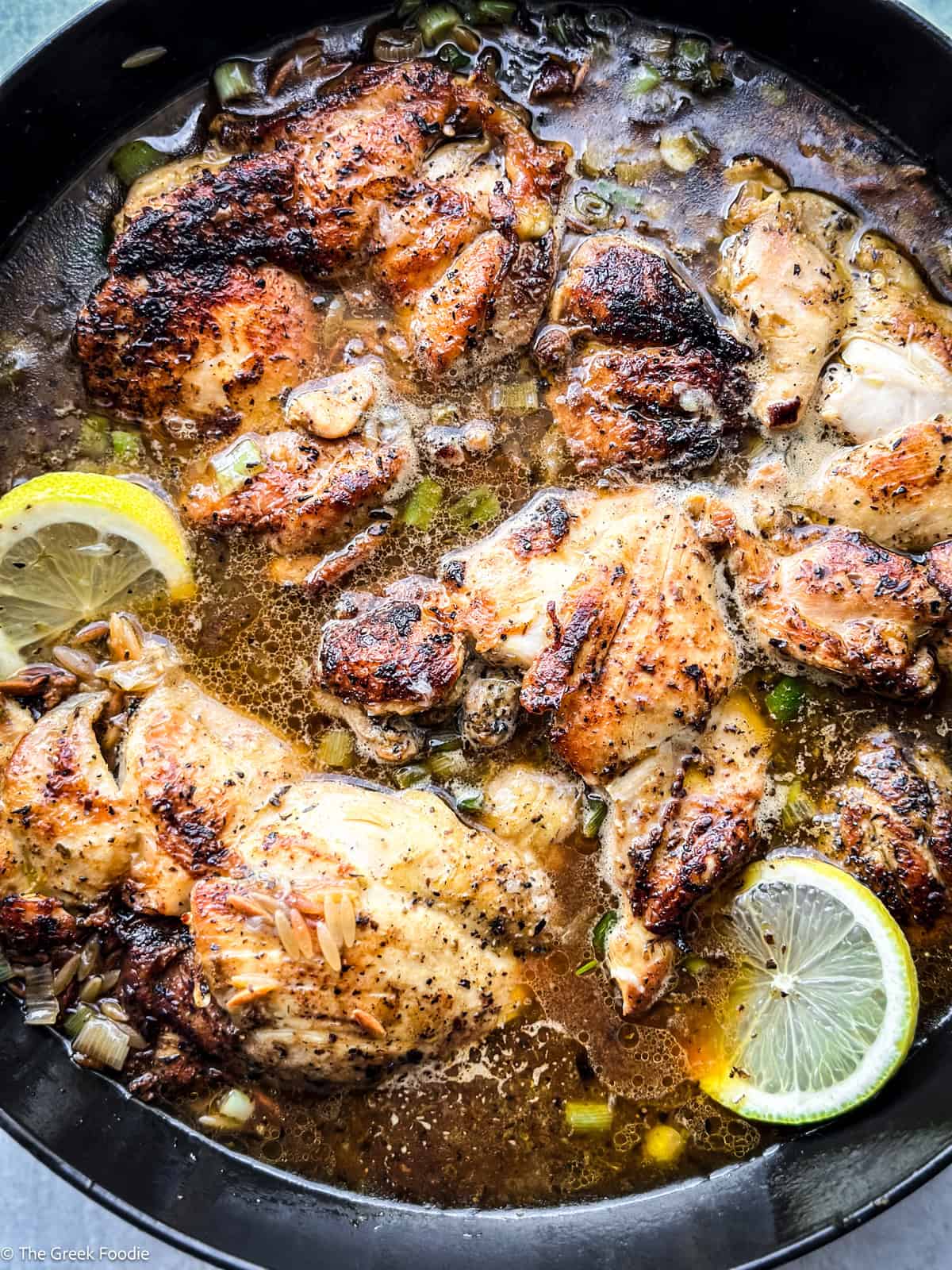 Chicken thighs in broth with lemon slices.