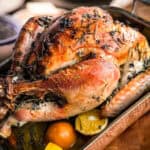 A roasted herb butter Christmas turkey in a copper pan on a table.