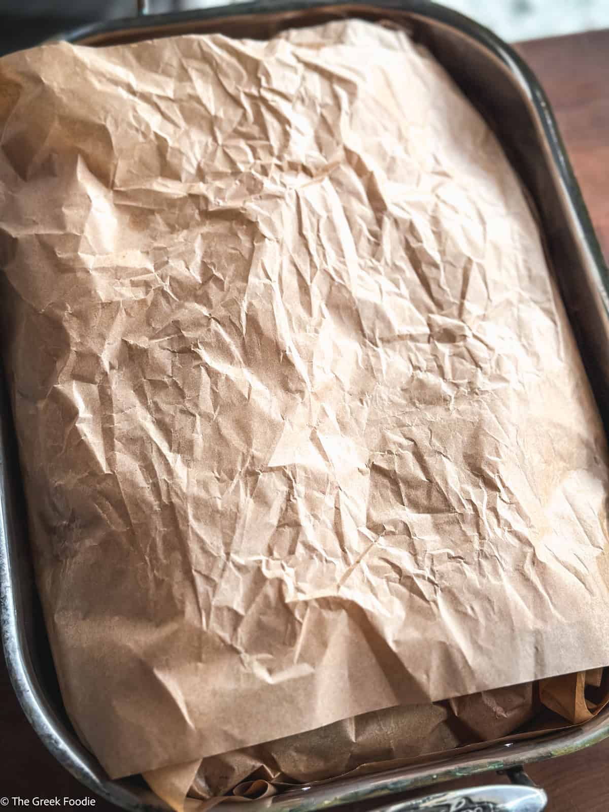 A parchment paper parcel in a roasting pan.