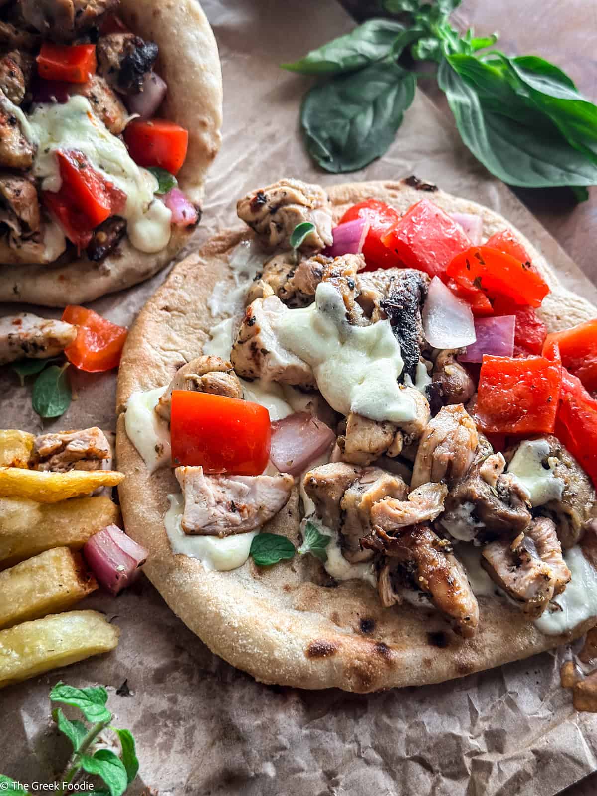 An open chicken souvlaki wrapped on paper, next to pita and fries.
