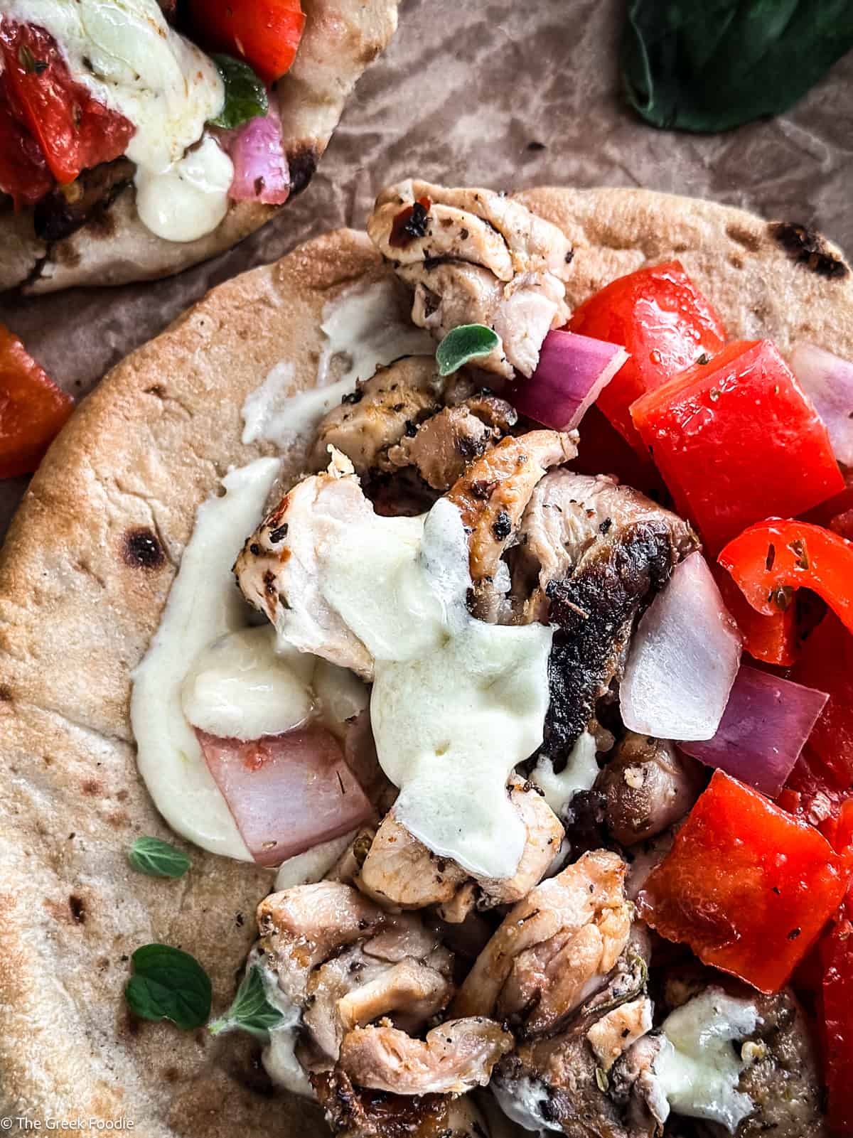 An open chicken souvlaki wrapped on paper, next to pita and fries.
