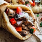 A chicken gyros souvlaki wrapped on paper, next to pita and fries.
