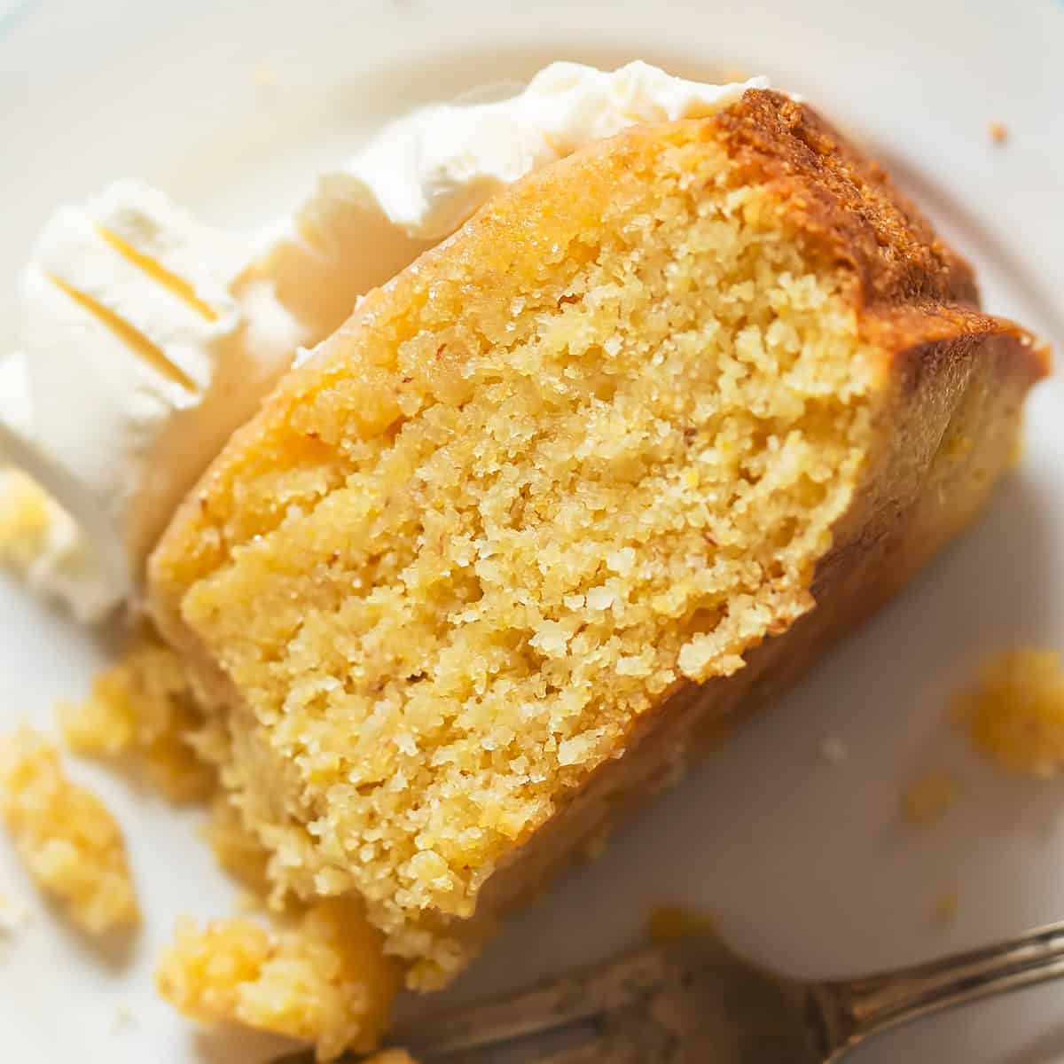 A piece of olive oil cake with ice cream on top on a plate.