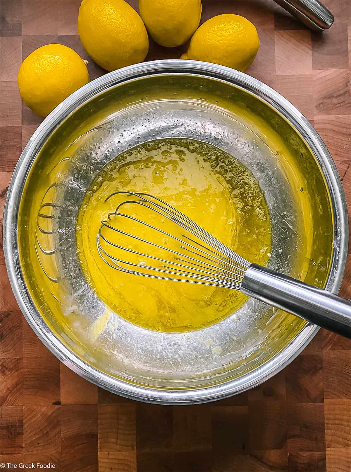 Eggs and olive oil in a bowl with a whisk.