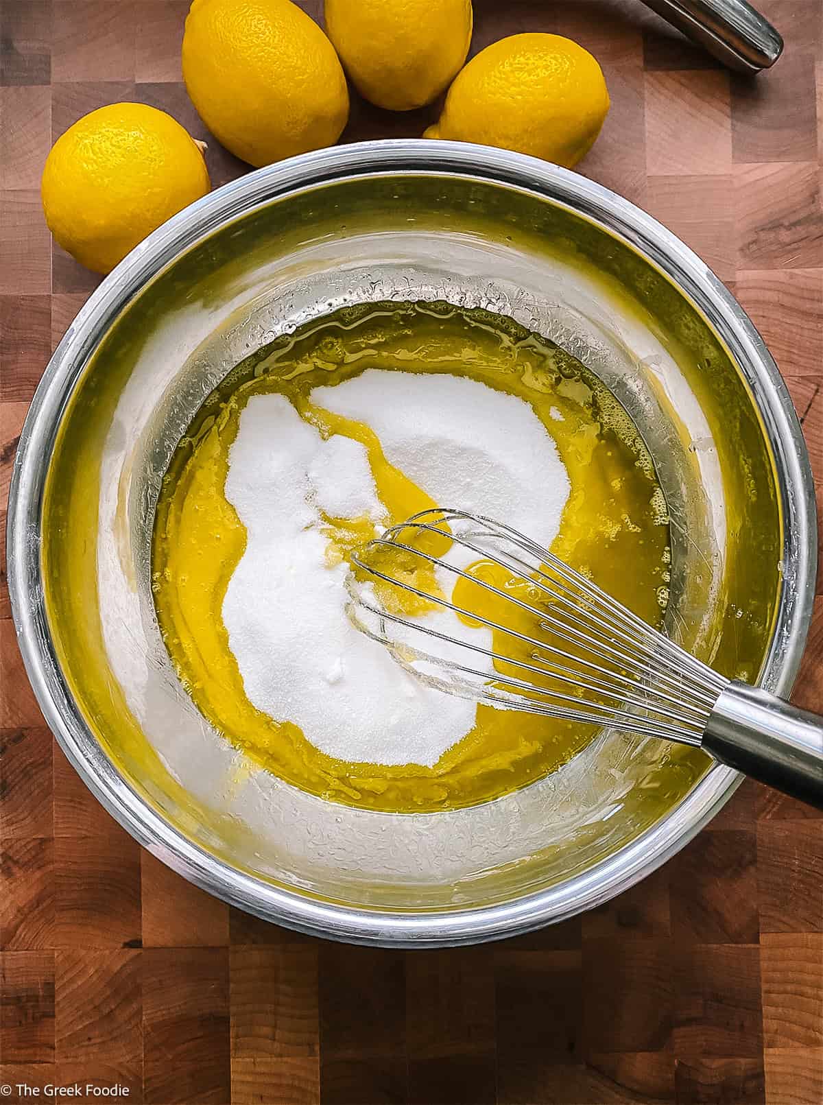Eggs and sugar in a bowl with a whisk.