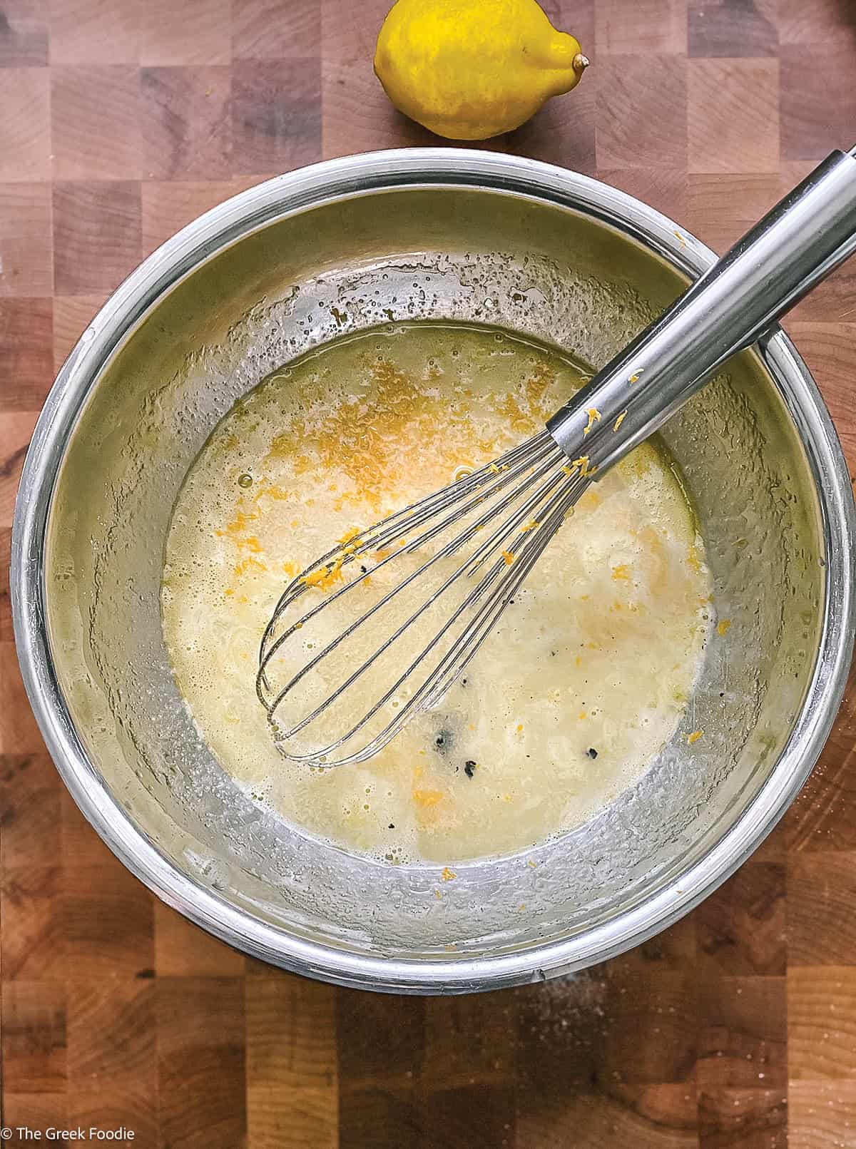 Eggs and sugar in a bowl with a whisk.