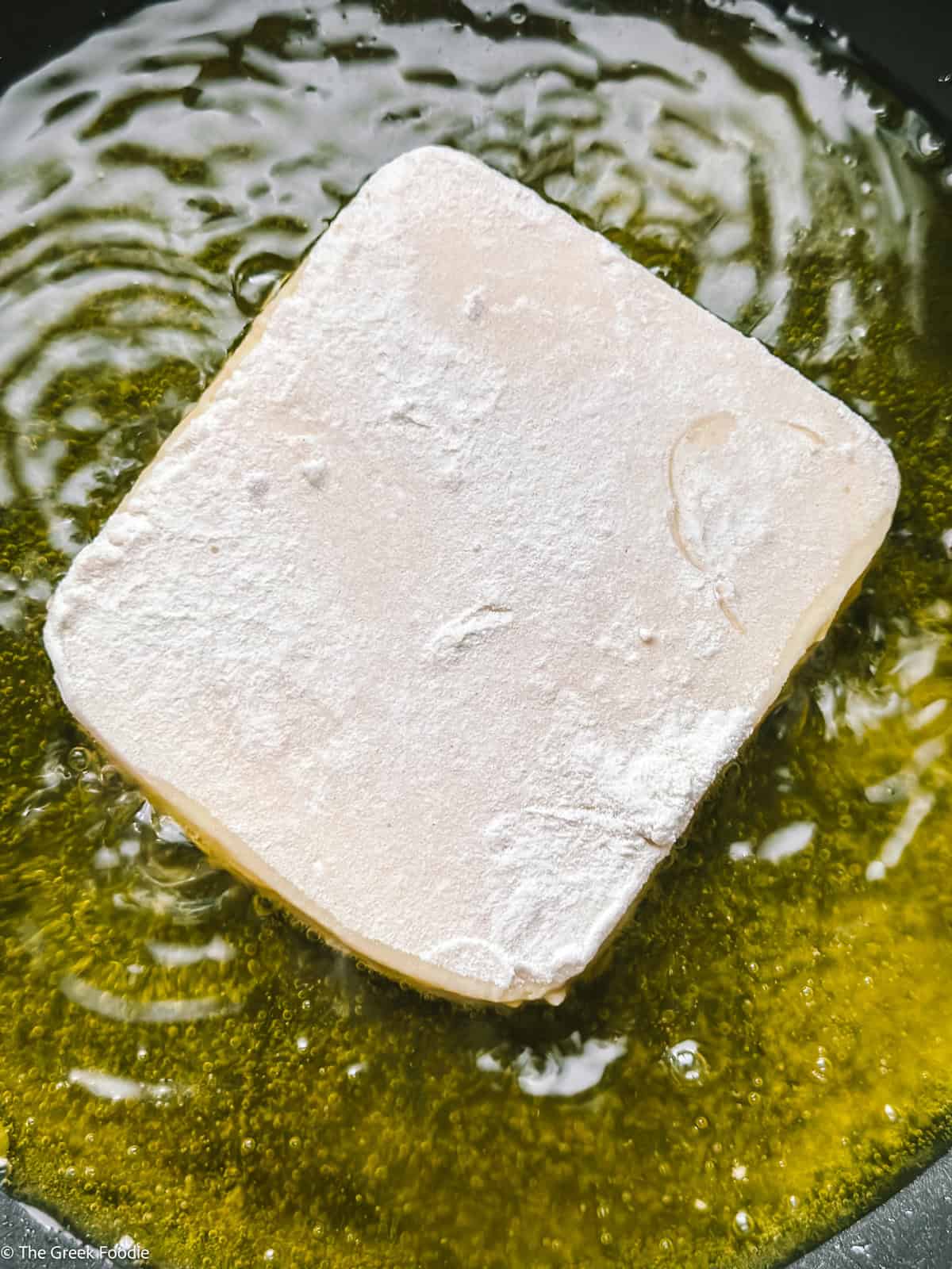 A piece of cheese frying in olive oil.