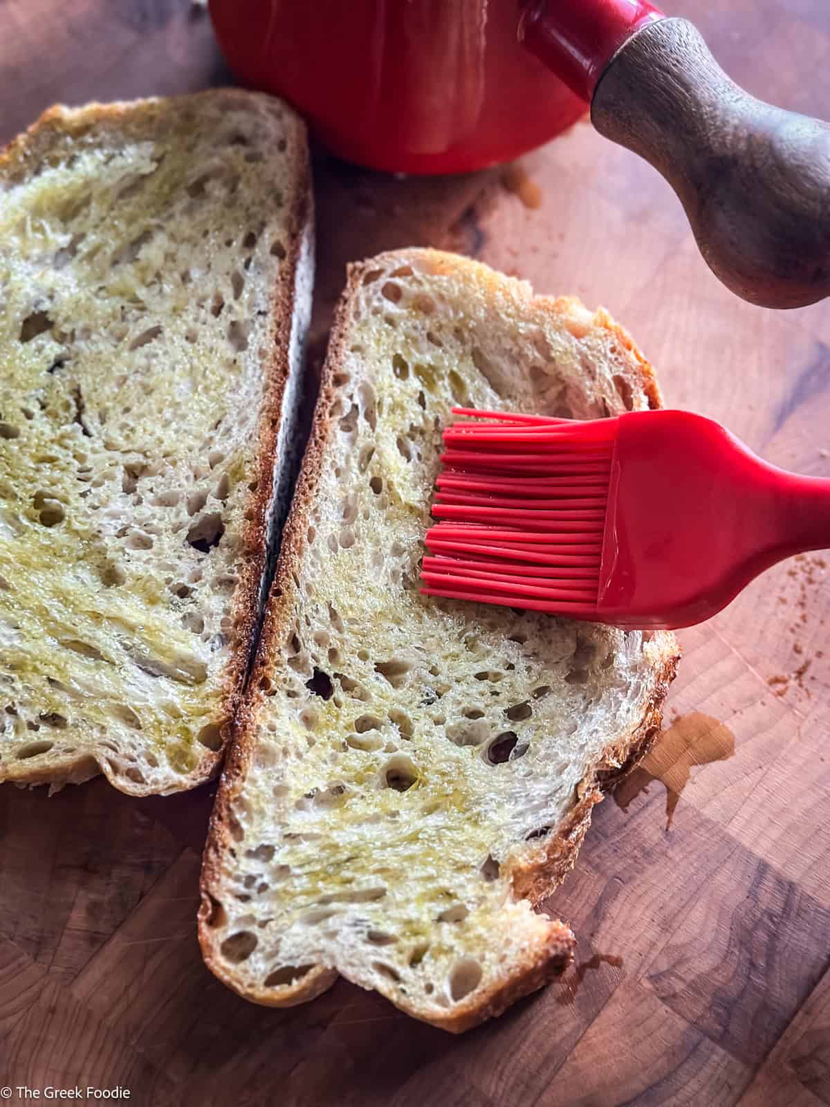 A brush brushing olive oil on bread.