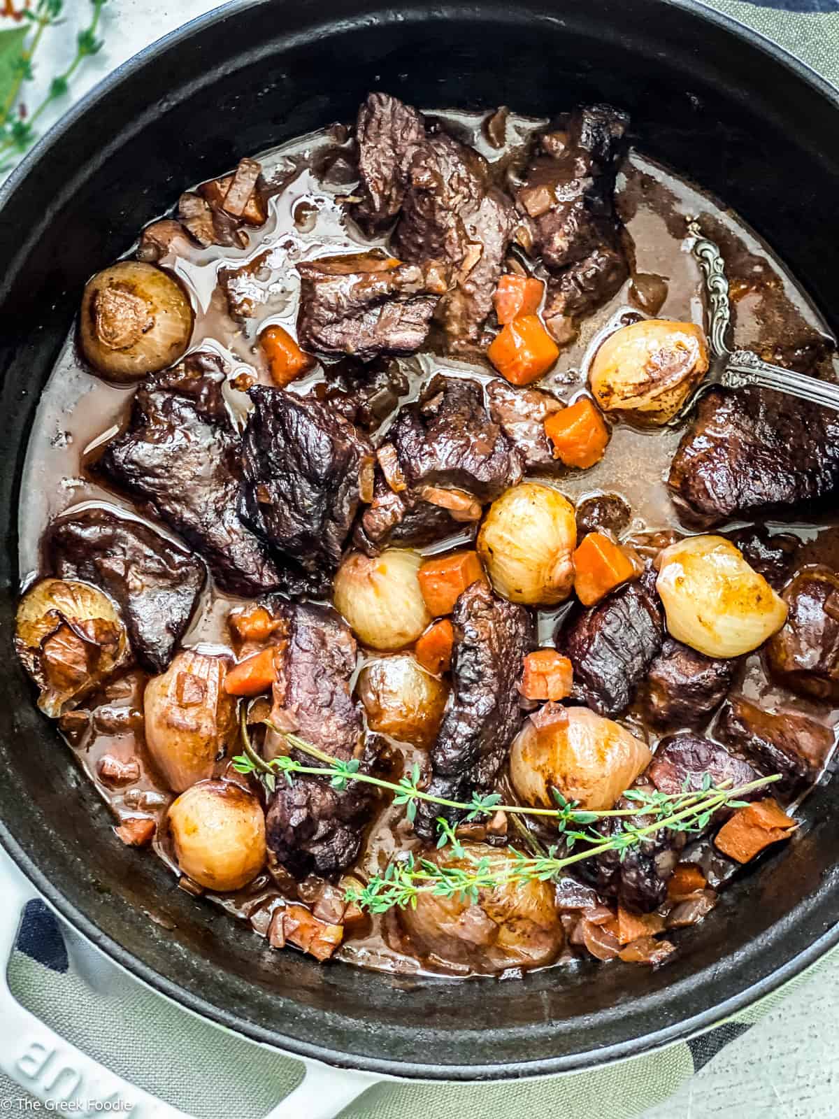 A white pot with Stifado-red wine beef stew on a white table.